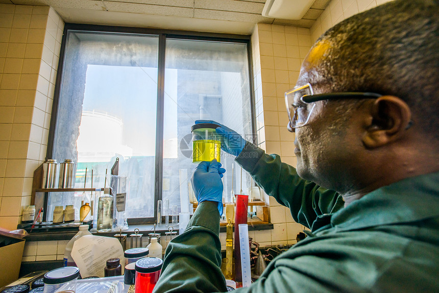 研究生物燃料工厂实验室中拿着黄色液体的实验室技术员图片