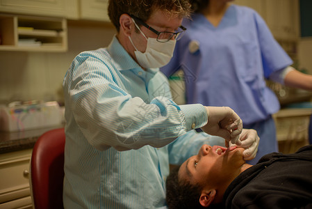 在牙医办公室治疗十几岁男孩的矫形医生图片