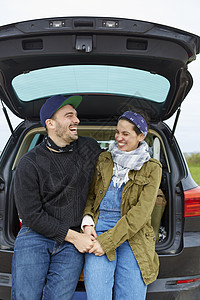 年轻夫妇坐在汽车后备箱图片