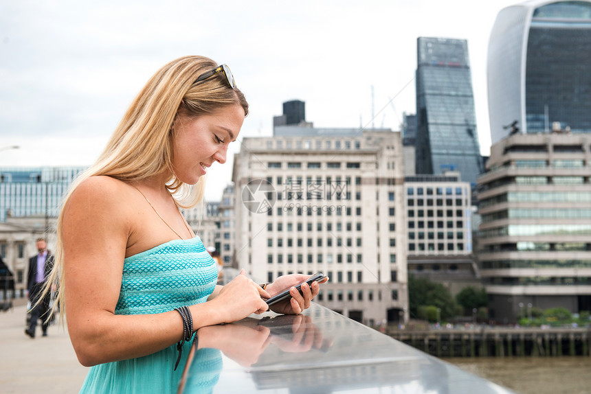 站在伦敦桥上使用手机的年轻女性图片
