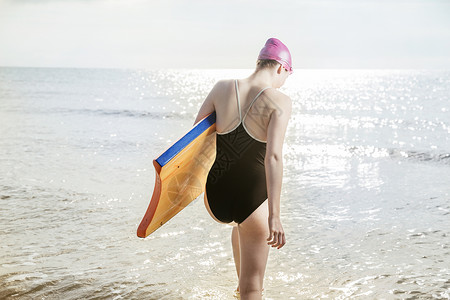 在联合王国的海上拿着冲浪板的年轻妇女图片
