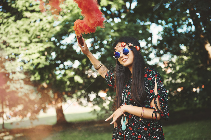 年轻女人在节日上举起红色烟雾弹图片