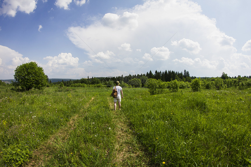 年轻男徒步旅行者沿农村泥土轨道徒步远足的近视图片