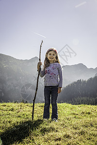 在日落的山地风景中走棍的快乐女孩肖像德国巴伐利亚图片