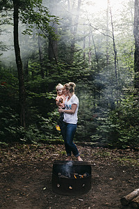 加拿大亨茨维尔母亲抱着女儿在森林篝火旁亲吻她的脸颊图片
