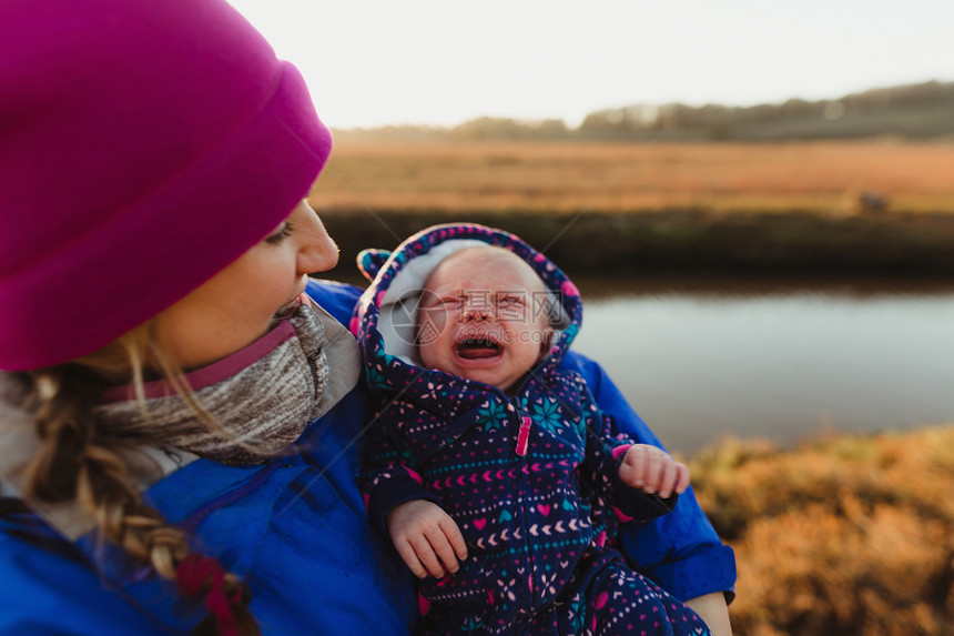 在美国加利福尼亚MorroBay河岸上哭着的女婴中年期成妇女摇欲坠图片