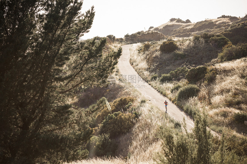美国加利福尼亚州圣巴巴拉市一名男子在空旷的道路上在农村丘陵地带的户外跑步图片