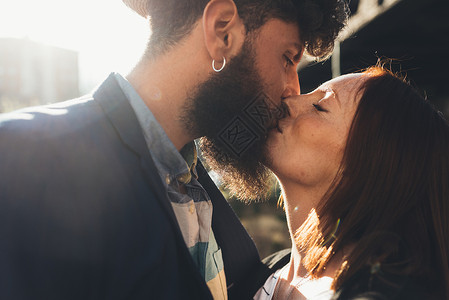 酷的一对情侣在阳光明媚的街道上接吻图片