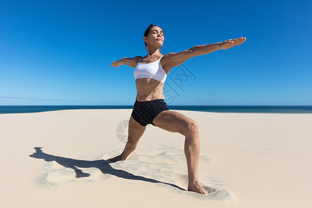 女人在沙滩手臂上张开柔瑜伽的伸展姿势图片