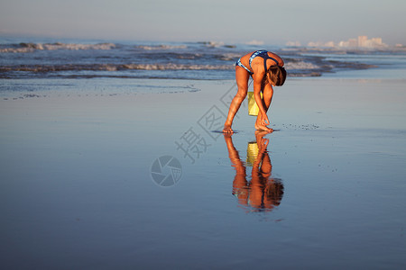 海滩上拎着水桶检贝壳的女孩背景