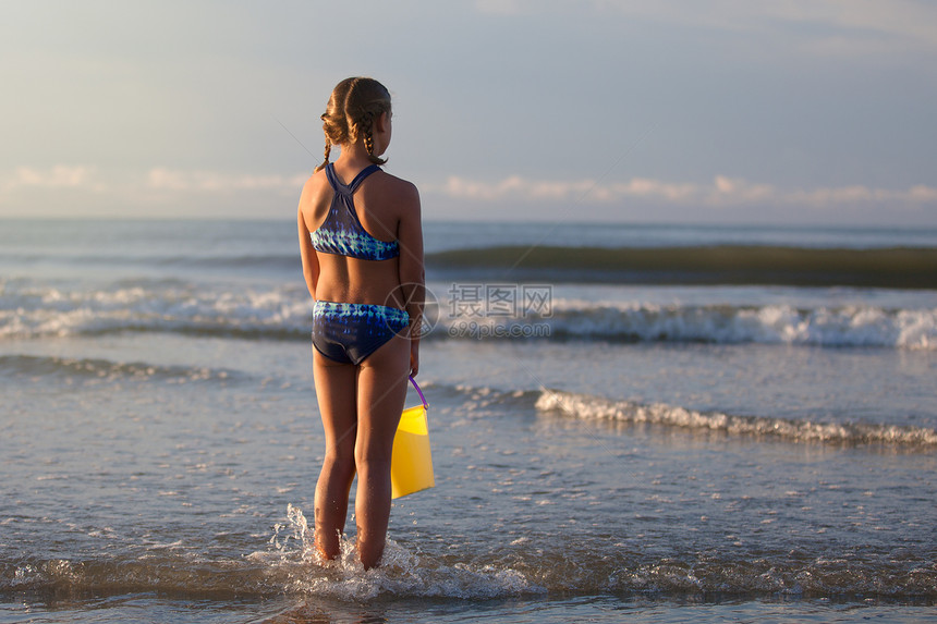 海滩上拎着水桶的女孩背影图片