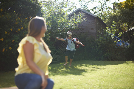 成年女子看儿跑在花园里身着飞行员服装在花园里跑图片