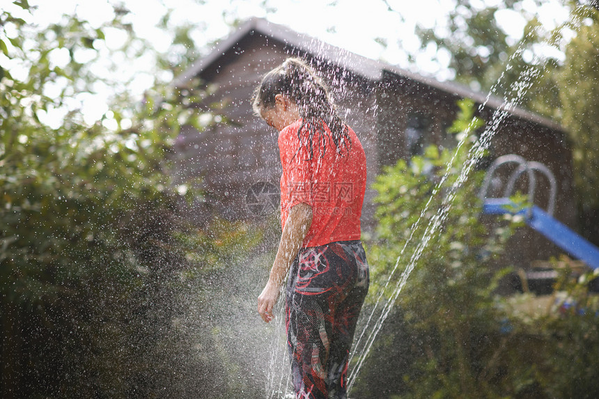 女孩站在花园喷洒器边图片