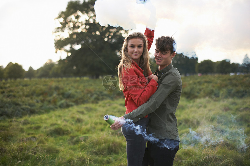 在野外放烟雾棒的年轻夫妇图片