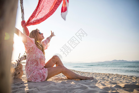 坐在海滩上手臂张开的女人图片