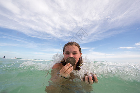 水中拿着贝壳的年轻女子的肖像图片