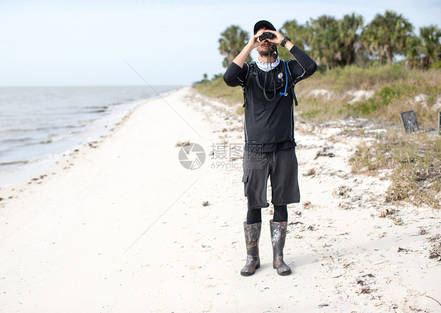 站在海滩上的人透过望远镜前视图片