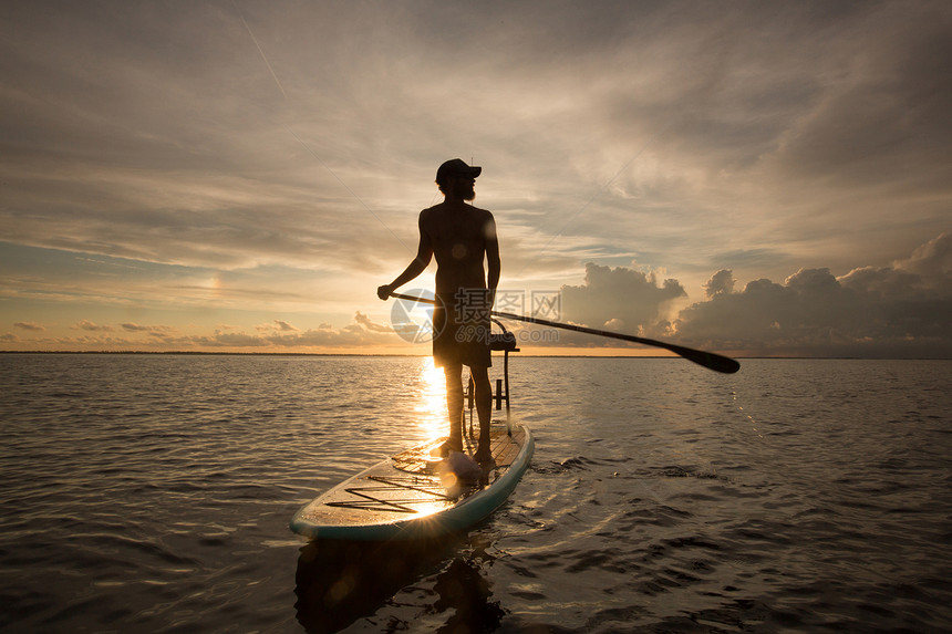 人站在桨板上水日落时图片