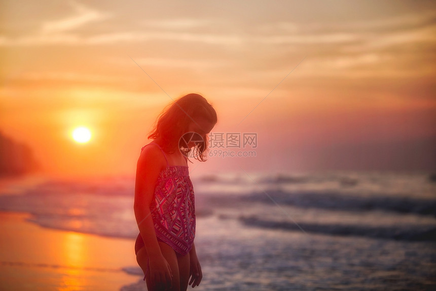 日落时海滩上的女孩剪影图片