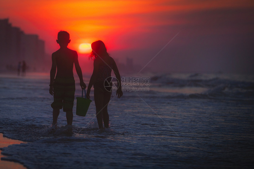 美国南卡罗来纳州北默特尔海滩日落时拎着水桶的兄弟姐妹图片
