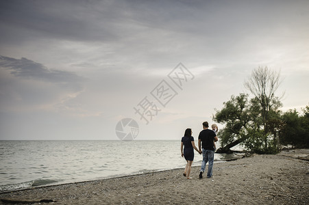 在加拿大安略湖海滩上与幼儿一起散步的情侣背景图片
