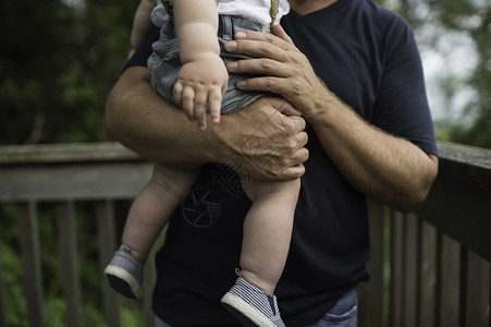 男人在阳台上抱着幼儿的手臂图片