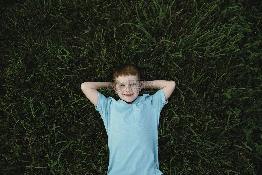 躺在草地上的红头发男孩图片