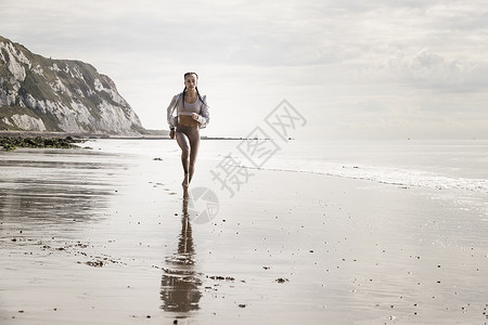 年轻女人赤脚在海滩的上跑步图片