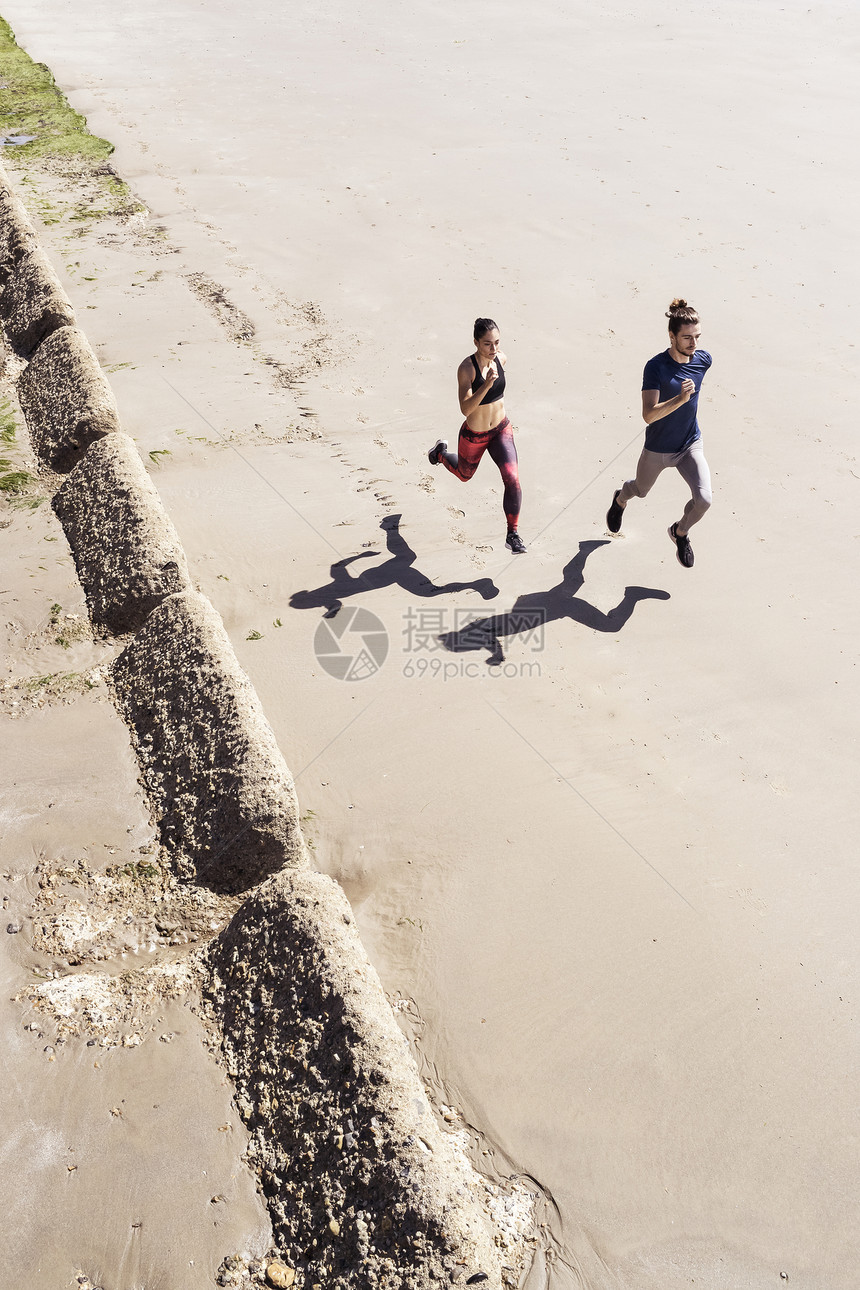 男女青年在海滩上奔跑图片