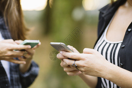 在公园两个女人使用手机的手图片
