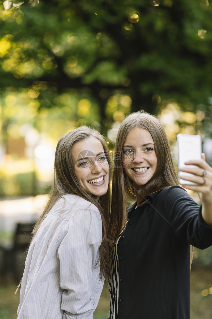 两名年轻女人在公园用手机自拍图片