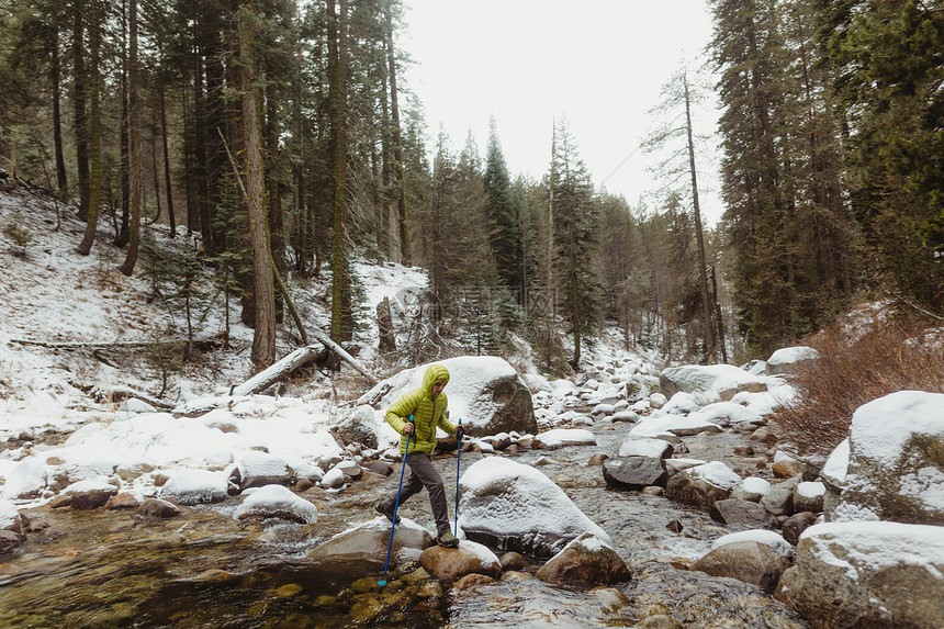 在美国加利福尼亚州雪地塞科公园男登山者跨过河流岩石图片