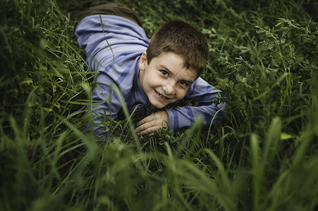 男孩在绿色草地上看着摄像头图片