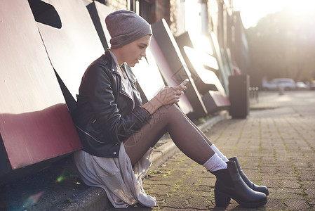 坐在街边玩手机的女青年图片