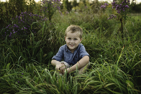 坐在草地看着镜头微笑的男孩肖像图片