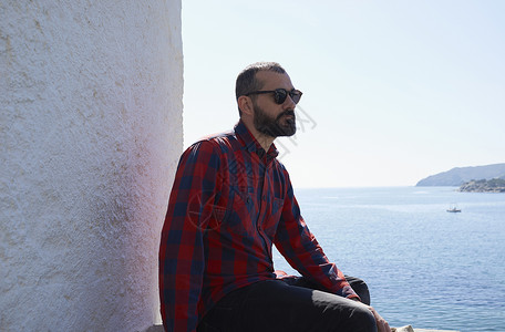 坐在西班牙安达卢亚塔里法安达卢西亚的塔里法海岸墙边的年轻男游客图片