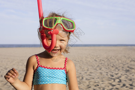海滩上穿潜水衣的女孩看着镜头笑图片