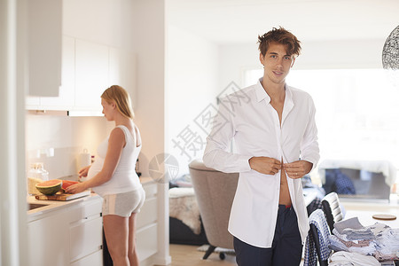 厨房里系衬衫扣子的男人和怀孕女友图片