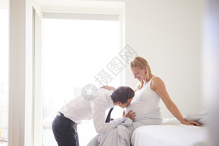 在卧室里亲吻怀孕女友肚子的男人图片