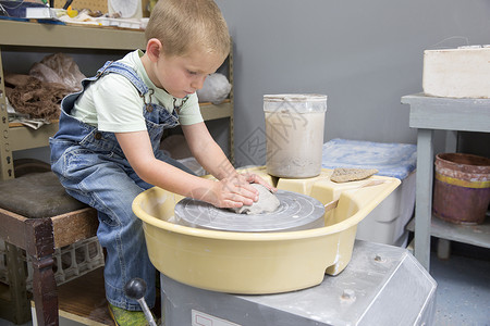 男孩在陶轮上给黏土塑形高清图片