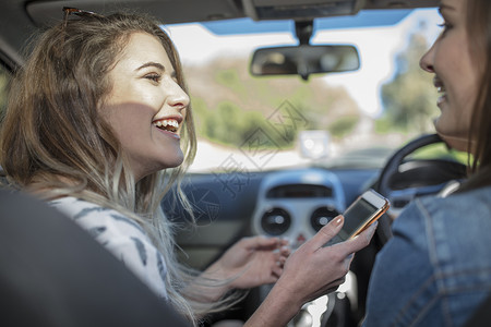 年轻女子与朋友一起开车手持智能机图片