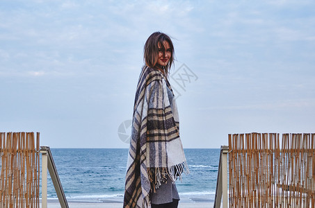 站在海滩附近裹着毯子的年轻女子图片
