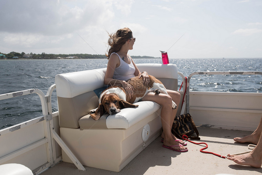 女人和宠物狗在船上放松图片