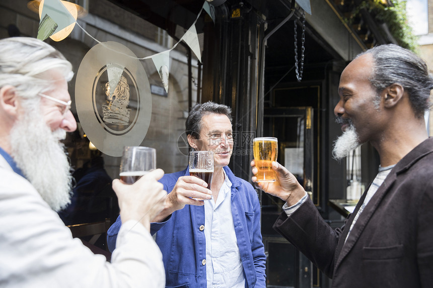 三个成熟的男人站在酒吧外面拿着啤酒敬杯图片
