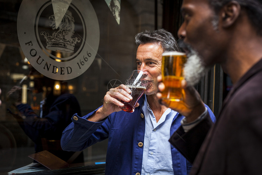 两个成熟的男人站在酒吧外面喝啤酒图片
