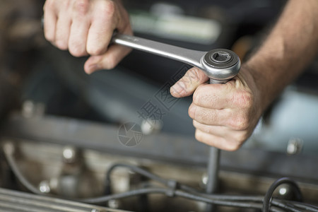 在修理车库使用扳手的男汽车机械手图片