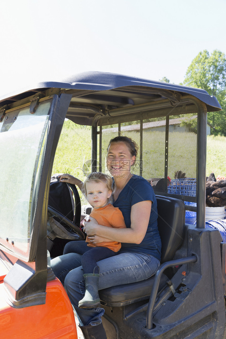 在自由牧场有机农的卡车上对女农民和幼儿图片