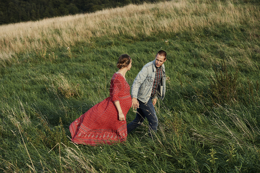 怀孕夫妇手牵手在田间散步图片