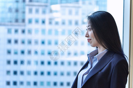 商务女性的肖像看着窗外的微笑图片
