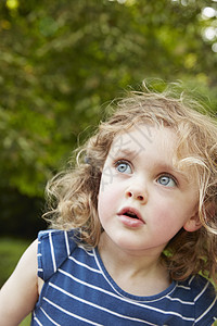 中等长度蓝眼金发的长卷女孩的肖像蓝眼睛在公园里凝视着背景